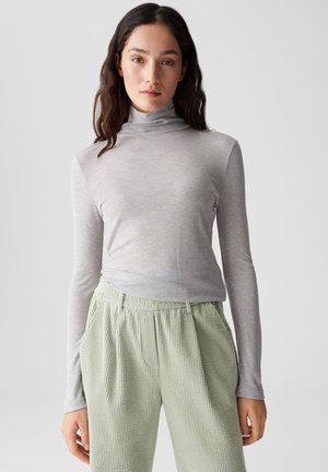 Grijze lange mouwen coltrui van zachte stof, gecombineerd met lichtgroene geribbelde textuurbroek met een elastische tailleband.