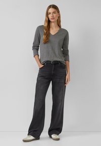 Gray v-neck sweater, black wide-leg jeans, and light sneakers. Smooth knit texture and straight cut. Simple design without patterns.
