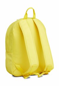 Mochila de tela amarilla con correas ajustables acolchadas, asa superior y cierre con cremallera. Presenta una forma redondeada y aerodinámica sin patrones.