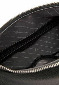 Black leather bag interior with a smooth texture, featuring a dark lining with thin gray stripes and a zippered pocket. Silver zipper closure.