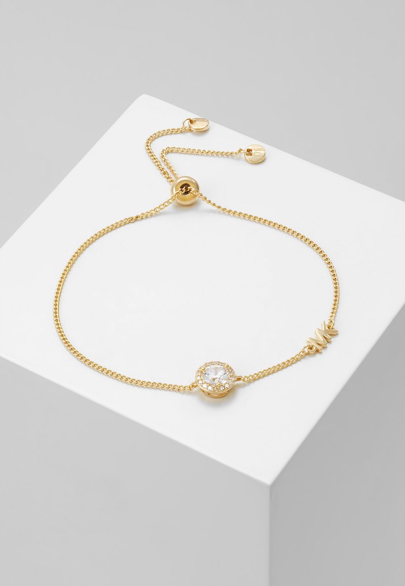 Pulsera de cadena de oro con una piedra clara redonda central rodeada de pequeñas piedras claras, con cierre ajustable y detalles en la cadena.