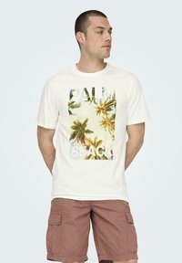 Camiseta blanca de algodón con un gráfico de palmera y el texto "PALM BEACH" en letras negritas. Diseño de manga corta y cuello redondo clásico.