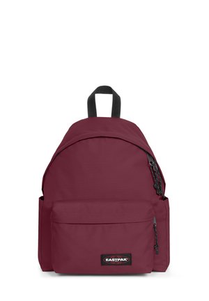 Mochila de tela roja con un borde curvado en la parte superior, asas ajustables, un bolsillo frontal y un parche con el logotipo. Presenta cremalleras y un acabado texturizado.