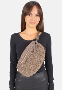 Braune Schaffell-Crossbody-Tasche mit einer weichen Textur, silbernem Reißverschluss und verstellbarem Tragegurt. Einzigartige ovale Form mit einer fusseligen Außenseite.