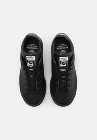 Baskets en cuir noir avec des bandes perforées, lacets plats et logo sur la languette. Bout arrondi et semelle texturée.