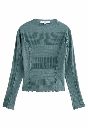 Langærmet tekstureret grøn strikbluse med flæsekant og vandrette stribemønstre, lagt fladt med front og ærmer synlige.