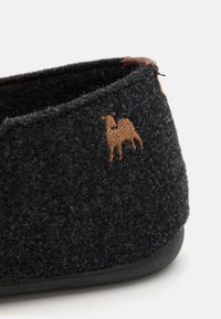 Sorte filt slippers med lav profil, der har en tekstureret overflade og et brunt broderet dyremotiv på siden.