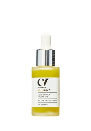 Yellow facial oil in a clear glass bottle, with a white dropper top. Label features black and gold text stating "AGE DEFY+ CELL ENRICH."