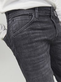 Vaqueros de denim gris oscuro con corte slim, que cuentan con un diseño clásico de cinco bolsillos, herrajes metálicos y detalles de textura sutiles.