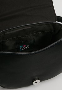 Černá kožená crossbody taška, otevřená, aby ukázala vnitřní tkaninovou podšívku a malou kapsu s etiketou značky Even & Odd.