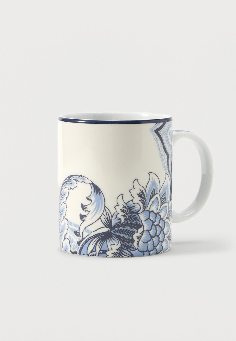 Tasse en céramique blanche avec motif floral bleu et bordure bleu foncé, anse à droite, sur fond blanc uni.