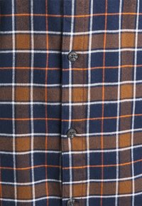 Camicia a quadri con una base blu navy, motivi a check marroni e arancioni, in cotone, con chiusura a bottoni e una morbida texture.