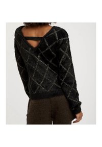 Czarny, puszysty sweter z głębokim dekoltem z tyłu, z krzyżowymi ramiączkami, w diamentowy wzór z srebrnymi nitkami oraz długimi rękawami. Teksturowany i przytulny materiał.
