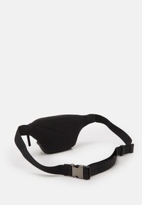 Musta vyölaukku, jossa on kolmiomainen muoto, pehmeä pinta ja vinosaumat. Varustettu mustalla säädettäväll ä hihnalla ja hopeasävyisellä soljella.