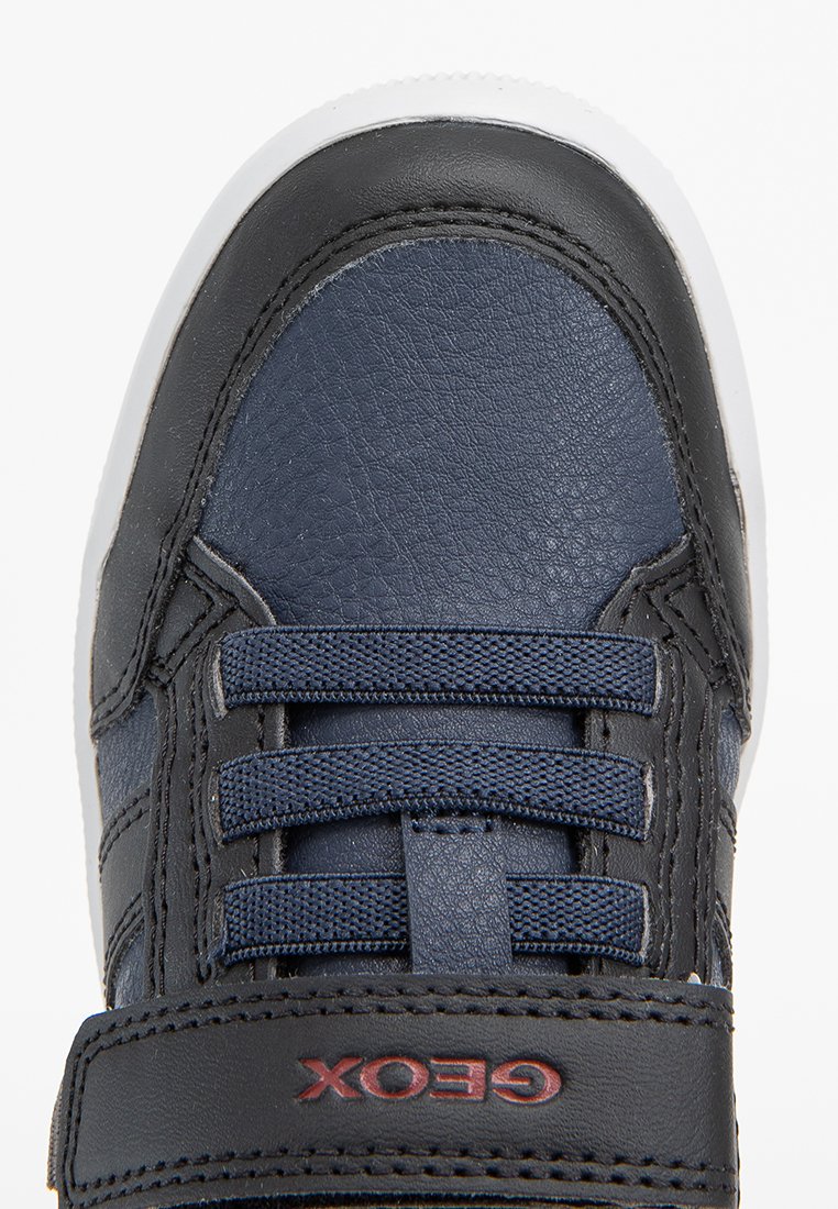 Baskets en cuir marine avec des accents noirs, semelle blanche et finition texturée. Elles disposent de lacets en tissu et d'une sangle avec logo sur la languette.