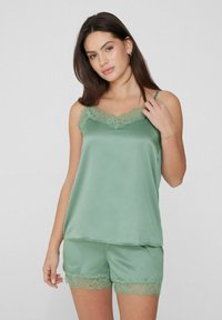 Ensemble de nuit en satin de couleur vert doux, comprenant un débardeur avec une finition en dentelle et un short assorti avec des bords en dentelle. Bretelles spaghetti ajustables.