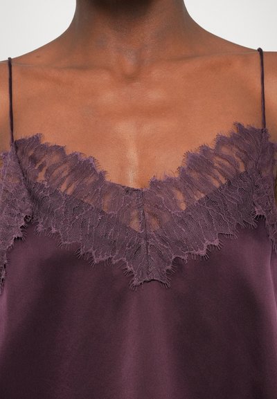 Sügavlilla siidist kampsun, mille kaeluses on peen pitsäär, millel on narmendavad ääred, õhukesed reguleeritavad rihmad ja sujuv tekstuur.