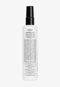 Spray desenredante en una botella blanca cilíndrica y transparente con un pulverizador negro; presenta texto impreso en varios idiomas en la parte posterior.