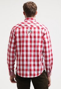 Camicia a maniche lunghe a quadri rossi e bianchi con polsini abbottonati, caratterizzata da una toppa sul retro e dettagli ricamati sulle spalle.
