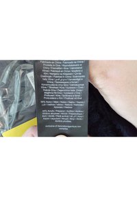 Black fabric care label featuring multiple languages, listing material composition: 56% nylon, 44% acrylic. Includes "Exclusive of decoration" note.