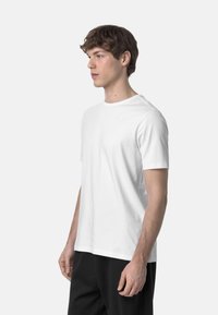 T-shirt bianca a maniche corte realizzata in cotone, con colletto tondo e un piccolo logo sul petto. Texture liscia, vestibilità comoda.