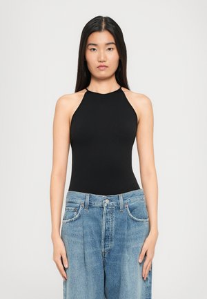 Black halter neck bodysuit with a fitted design, paired with loose-fit light blue denim jeans. Smooth texture, minimalistic style.