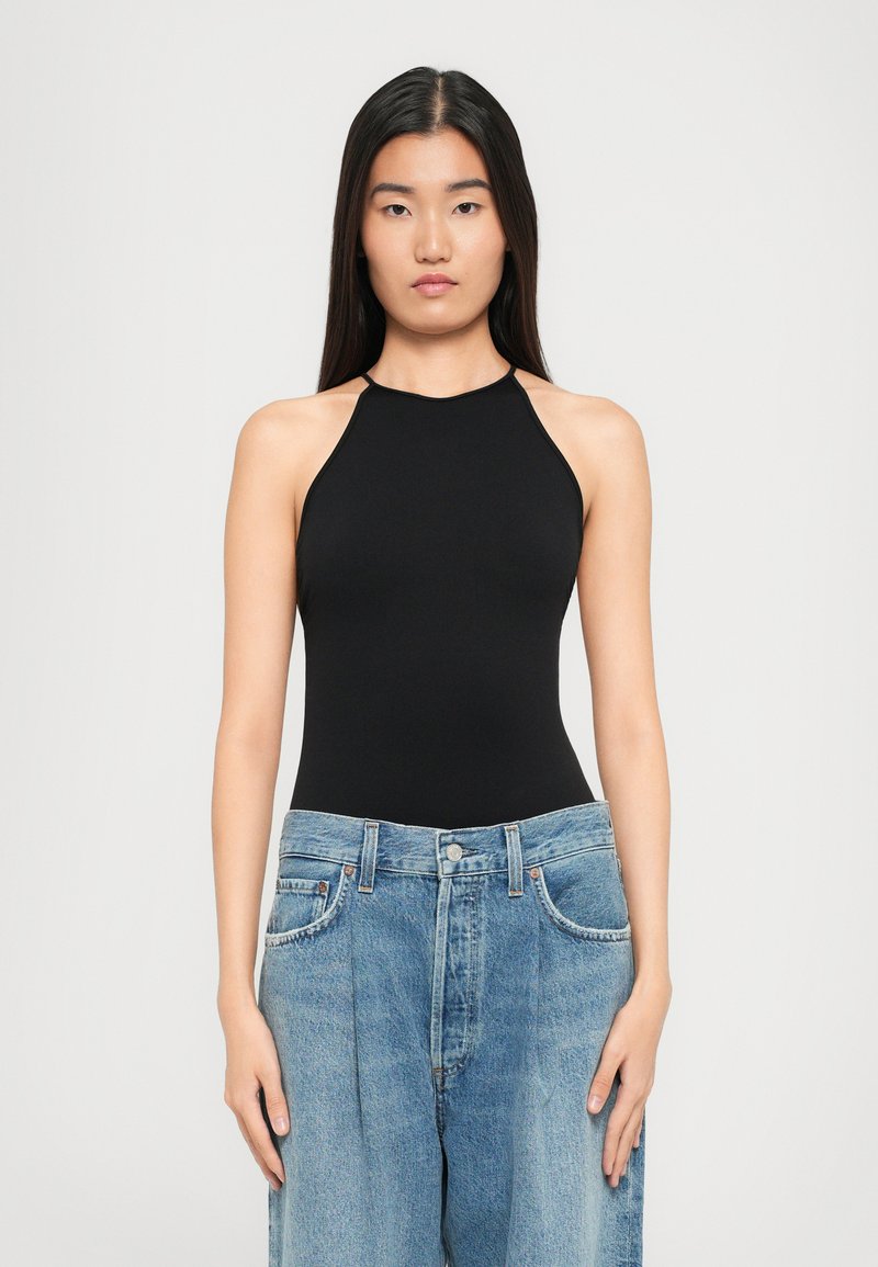 Bodysuit noir à col halter avec une coupe ajustée, associé à un jean en denim bleu clair à coupe ample. Texture lisse, style minimaliste.