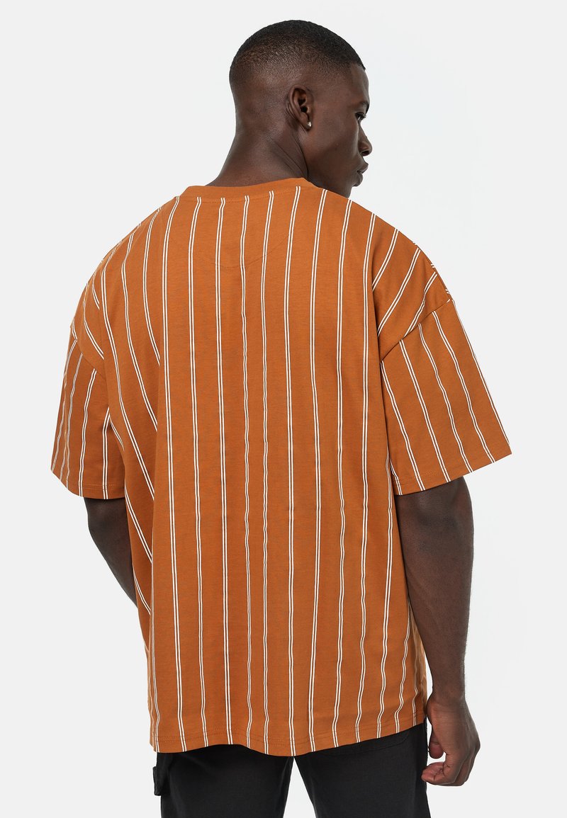 Brunstripete oversized t-skjorte med hvite vertikale striper, laget av bomull, med korte ermer og en avslappet passform, sett fra baksiden.