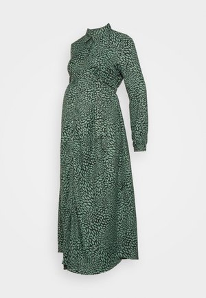 Long-sleeved, ankle-length maternity dress in dark green with a lighter green leaf pattern and a high neckline with buttons.