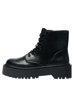 Botte de combat en cuir noir à lacets avec semelle plate-forme épaisse et bande de roulement robuste, fermeture éclair latérale et design montant à la cheville.