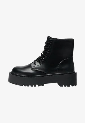 Botte de combat en cuir noir à lacets avec semelle plate-forme épaisse et bande de roulement robuste, fermeture éclair latérale et design montant à la cheville.
