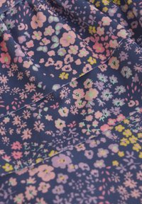 Blommönstrad tyg i marinblått med små, pastellfärgade blommor i rosa, gult och grönt. Mjuk textur med ett flödande mönster.