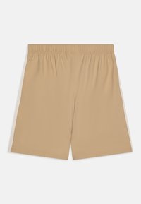 Shorts de sport beiges avec une taille élastique, en tissu uni, et des panneaux latéraux en mesh blanc contrastant.