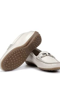 Mocasines de cuero blanco con acentos decorativos en plata y suela de goma texturizada con agarres redondeados. Superficie lisa con costuras detalladas.
