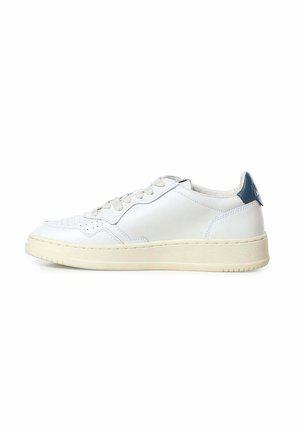 Zapatilla blanca de caña baja con suela y cordones beige, con detalles perforados en la puntera y lengüeta azul en el talón.