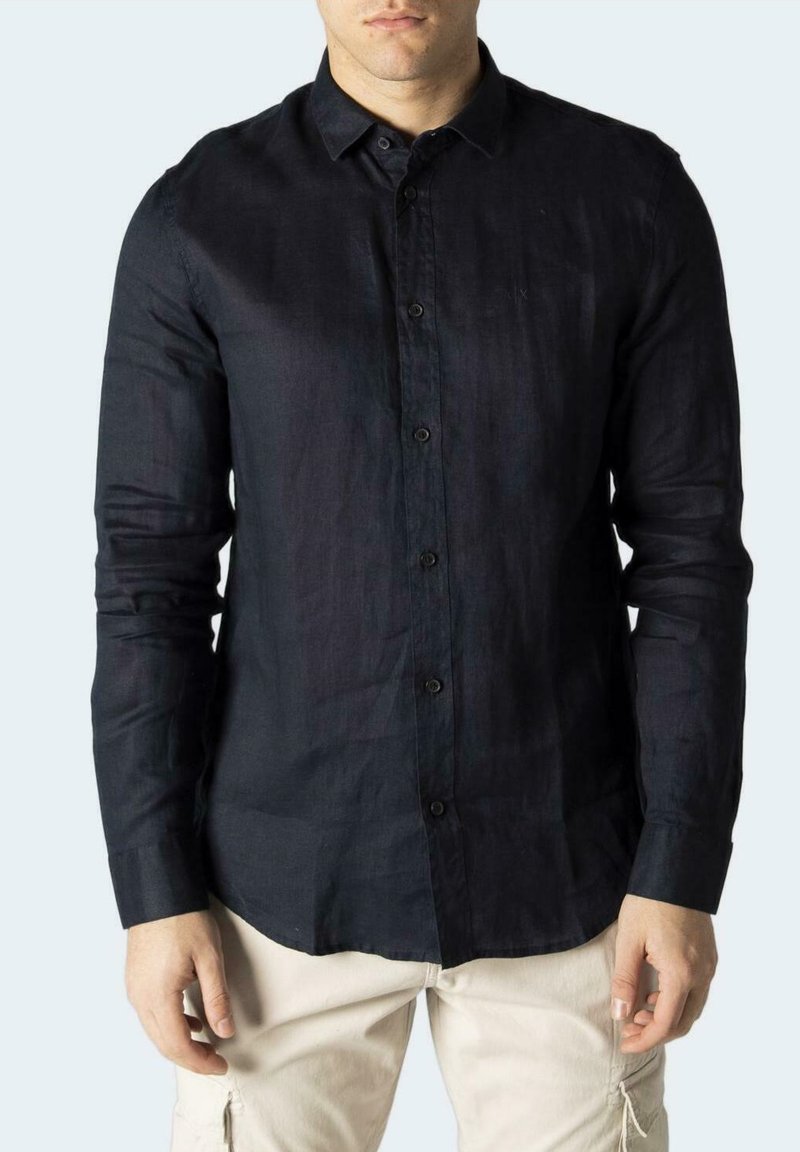 Camicia di lino blu navy con bottoni, maniche lunghe e design aderente. Presenta un colletto classico e una texture liscia.