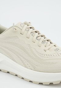 Beige Sport Schuh mit Mesh- und strukturiertem Synthetik-Obermaterial. Verfügt über ein erhöhtes Swoosh-Design, flache Schnürsenkel und eine gepolsterte weiße Sohle.
