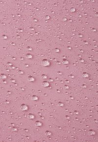 Różowa tkanina o teksturowanej powierzchni z wieloma kroplami wody o różnych rozmiarach, podkreślająca jej właściwości wodoodporne.