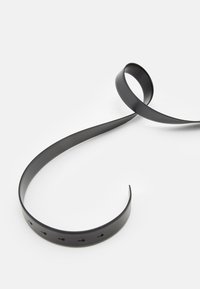 Čierny gumový remienok s hladkým povrchom, disponujúci viacerými otvormi na nastavenie, zvinutý a položený na bielom pozadí.