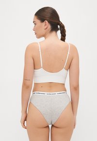 White ribbed bralette with adjustable straps and a gray high-waisted brief featuring a black "BJÖRN BORG" waistband, with a smooth texture.