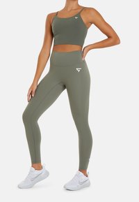 Sujetador deportivo color verde oliva y leggings a juego con un diseño entallado. Ambas prendas tienen un detalle de logo y están hechas de una tela suave y elástica.
