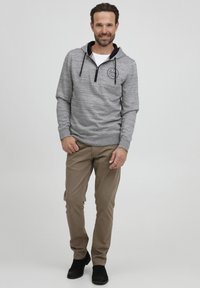 Gray pullover hoodie with a quarter-zip, textured fabric, and navy accents. Paired with tan pants and black shoes, standing against a light background.