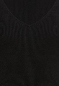 Tissu en maille côtelée noire avec un col en V, montrant une texture détaillée et de fines lignes verticales.