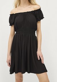 Schwarzes, schulterfreies Kleid aus weichem Stoff, mit gerafftem Detail an der Taille, kurzen Puffärmeln und einem ausgestellten Rock.