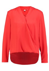 Blouse rouge style portefeuille avec col en V, manches longues et panneau transparent à l'ourlet. Tissu lisse avec une finition légèrement brillante.