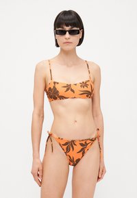 Pomarańczowe bikini z brązowym wzorem kwiatowym; zawiera regulowane ramiączka na górze i majtki z wiązaniem po bokach; gładki materiał.