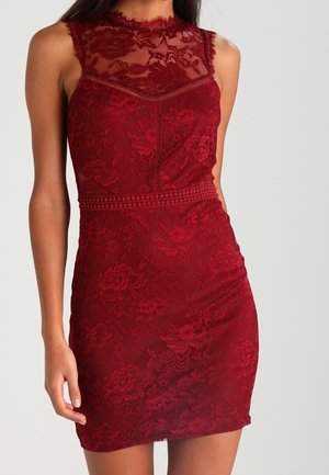 Robe en dentelle rouge avec un col montant, un motif floral, une silhouette ajustée et un buste texturé, accompagnée d'une jupe lisse légèrement évasée.