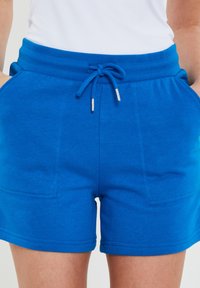 Modré bavlněné šortky s elastickým pasem, stahovací šňůrkou a dvěma předními kapsami. Hladký povrch s viditelnými detaily prošívání.