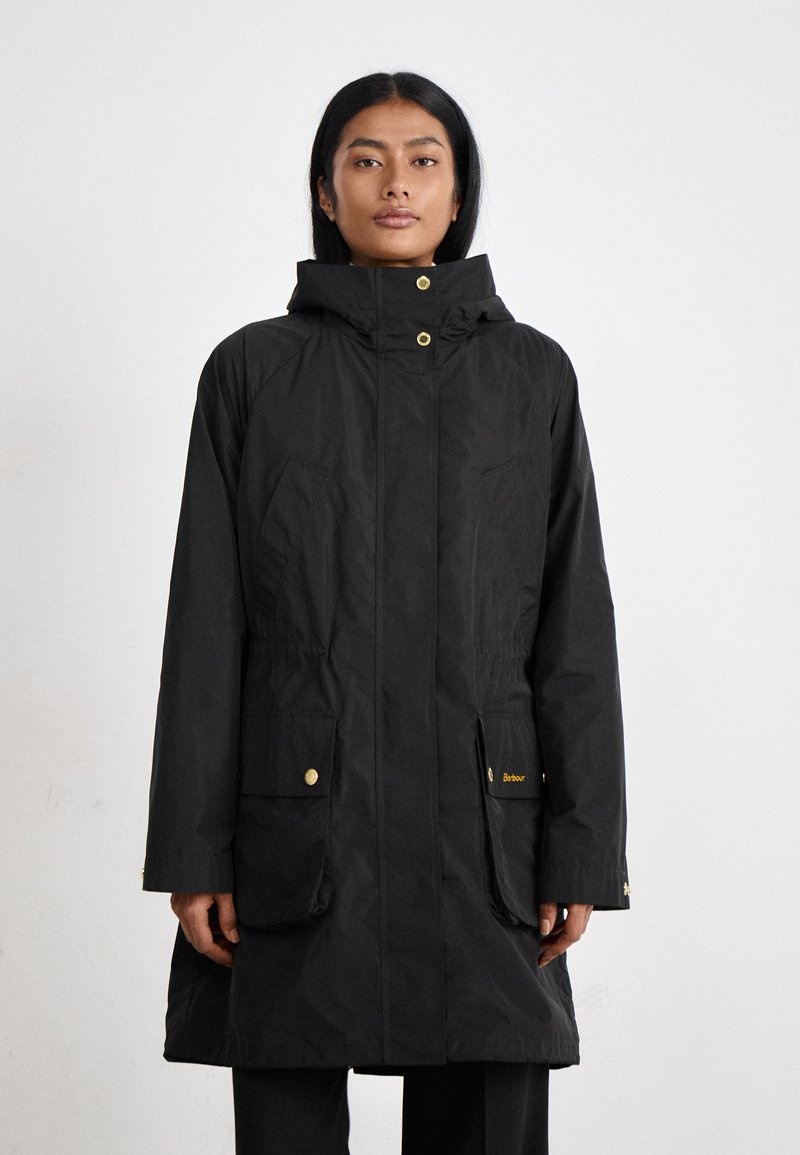 Zwarte waterdichte parka-jack met gouden hardware, voorzakken, verstelbare capuchon en elastische taille details. Gladde textuur en knielange ontwerp.