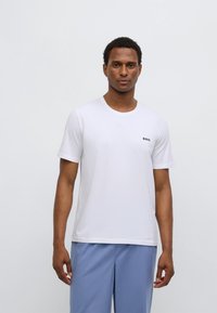 T-shirt bianca a maniche corte con collo rotondo, con un piccolo logo nero "BOSS" sul petto a sinistra, realizzata in morbido tessuto di cotone.